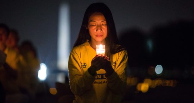 A woman joins Falun Gong practitioners holding a candlelight vigil at the Lincoln Memorial in Washington D.C., on July 20, 2017, to honor those who have died during the persecution in China that the Chinese regime started on July 20, 1999. (Benjamin Chasteen)
