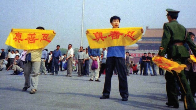 A Chinese policeman (right) approaches Falun Gong practitioners on Tiananmen Square as they hold a banner that reads "Truthfulness Compassion Forbearance"